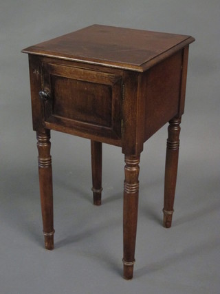 A 19th Century mahogany bedside cabinet enclosed by a panelled  door, raised on turned supports 15"