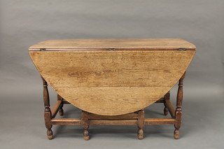 An 18th Century honey oak oval drop flap gateleg dining table with 2 frieze drawers, raised on turned and block supports 49"