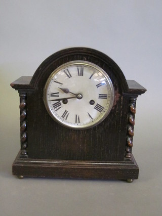 A 1920's striking mantel clock with silvered dial and Roman  numerals contained in an oak arch shaped case