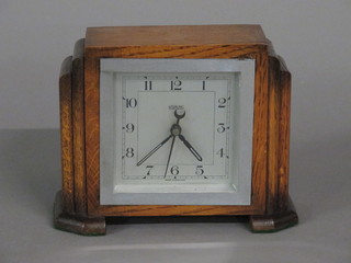 An Art Deco electric mantel clock with silvered dial and Arabic numerals contained in an oak case by Sterling Tan