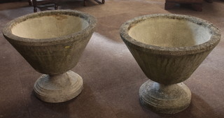 A pair of circular stoneware garden urns raised on circular supports 24"