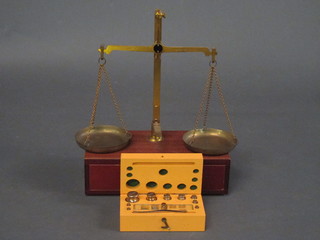 A pair of brass pan scales, the base fitted a drawer and a box  with hinged lid containing various weights and 2 spring balances