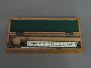 A precision instrument comprising shaped glass tube contained  in an oak case with hinged lid