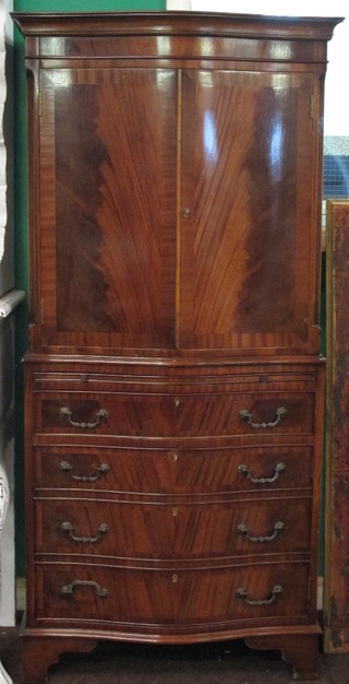 A Georgian style mahogany cabinet of serpentine outline, the upper section with moulded cornice fitted a cupboard enclosed by  a panelled door, the base fitted a brushing slide above 4 long  drawers, raised on bracket feet 28"