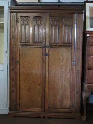 A 1930's carved oak wardrobe with moulded cornice enclosed  by arched shaped panelled doors 49"