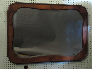 A shaped bevelled plate wall mirror contained in a walnut frame  34"