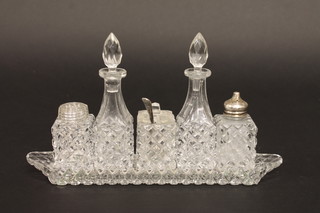 A cut glass 5 piece condiment set with the pepper with silver lid, raised on a boat shaped stand, together with a silver plated  mustard spoon