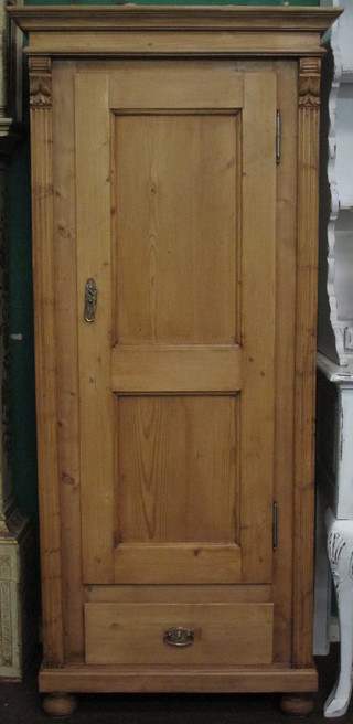 A Continental stripped and polished pine cupboard with moulded cornice and shelved interior enclosed by a panelled door, the base  fitted drawer, raised on bun feet 30"