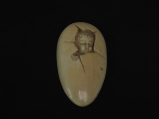 A 19th Century carved ivory plaque depicting a child emerging  from an egg 3 1/2", the reverse with old label