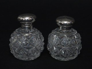 A pair of globular cut glass scent bottles complete with stoppers and hinged silver lids, Birmingham 1918