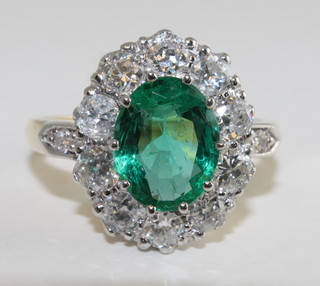 An 18ct yellow gold dress ring set an oval cut emerald  surrounded by diamonds approx. 1.20/1.30ct