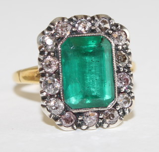 A An 18ct yellow gold dress ring set a rectangular cut emerald supported by diamonds approx. 0.80/2.15ct