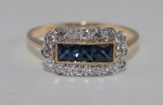 An 18ct yellow gold dress ring set square cut sapphires supported by diamonds