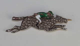 A gold and enamelled brooch in the form of a race horse with  jockey up, the horse set diamonds