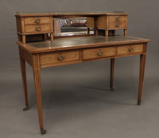 A Victorian inlaid mahogany writing table, the raised mirrored back with three-quarter gallery fitted 2 short drawers, inset a  tooled green leather writing surface above 3 long drawers, raised  on square tapering supports ending in brass caps and castors, by  Shoolbred & Co 48"  ILLUSTRATED