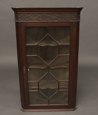 A Chippendale style mahogany hanging corner cabinet with  moulded cornice and blind fret work decoration, the shelved  interior enclosed by an astragal glazed panelled door 24"