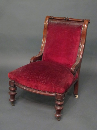 A Victorian mahogany show frame nursing chair upholstered in  red material, raised on turned supports