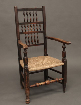 An elm spindle back carver chair with woven rush seat