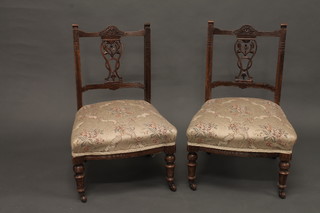 A pair of Edwardian walnut nursing chairs with pierced vase shaped slat backs and upholstered seats, raised on turned supports