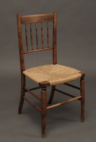 An elm stick and rail back chair with woven rush seat raised on turned supports