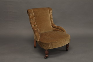 A Victorian mahogany framed nursing chair upholstered in  mushroom coloured material, raised on turned supports