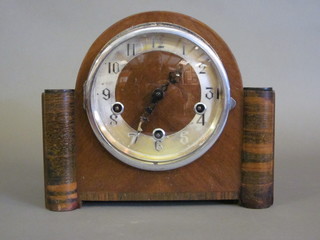 An Art Deco chiming mantel clock with Arabic numerals  contained in a walnut arch shaped case