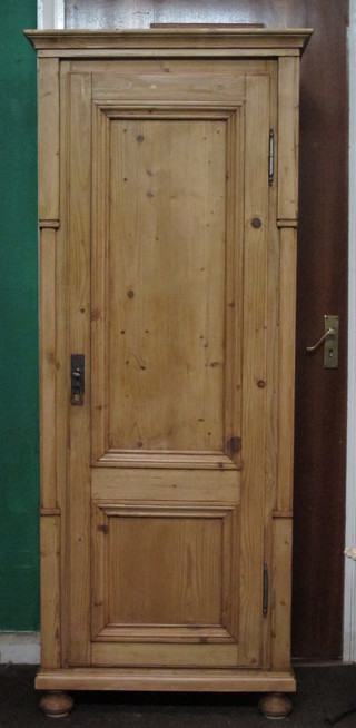 A Continental polished pine cabinet with moulded cornice and shelved interior enclosed by panelled doors, raised on bun feet  27"