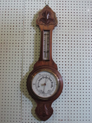 An aneroid barometer and thermometer with enamelled dial contained in a honey oak wheel case, glass cracked,