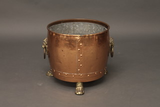 A circular copper log bin with brass lion marks handles and paw feet 16"