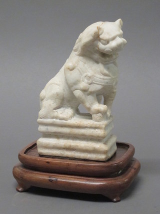 A carved soap stone figure of a Dog of Fo, raised on a wooden stand 7"