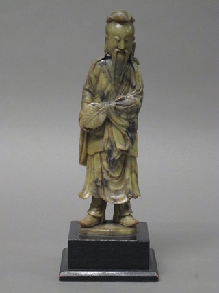 A soap stone figure of a standing sage raised on an ebonised base  10"