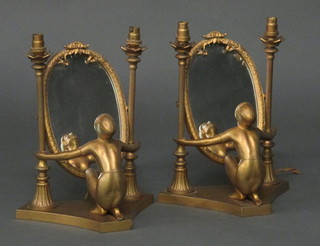 A pair of Art Deco metal dressing table lamps in the form of  seated semi-naked ladies supporting oval plate mirrors   ILLUSTRATED