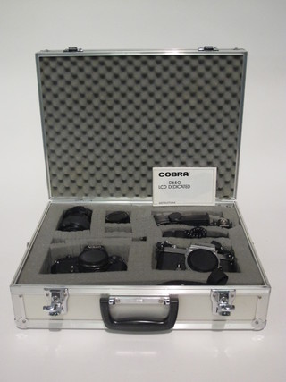 A metal camera case containing a Nikon camera, a Nikkormat camera and 2 lenses