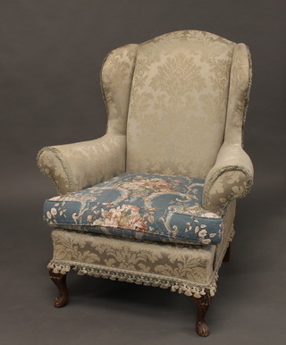A 1930's Queen Anne style winged armchair upholstered in blue material and raised on cabriole supports