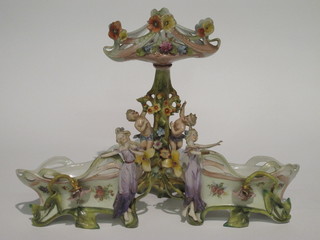 An Edwardian Art Nouveau 3 piece porcelain garniture  comprising twin handled bowl supported by cherubs and a pair of  basket shaped urns decorated flowers, 1 f and r,