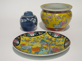 A circular Oriental yellow glazed fish bowl 9", a Japanese yellow and black glazed bowl 14" and a prunus ginger jar and cover