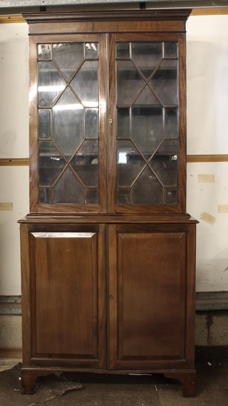 A 19th Century mahogany bookcase on cabinet, the upper section  with moulded cornice, the shelved interior enclosed by astragal  glazed panelled doors, the base fitted a cupboard enclosed by  panelled doors, raised on bracket feet 35"