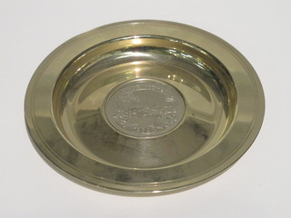 A circular white metal dish set a coin