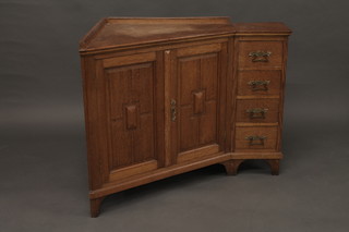 An Arts & Crafts honey oak corner cabinet enclosed by panelled doors and flanked by 4 short drawers 36"