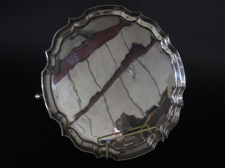 A circular silver salver with bracketed border, raised on panel supports, Sheffield 1971, 31 ozs
