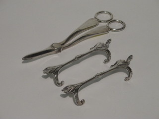 A pair of silver plated grape scissors and a pair of silver plated knife rests