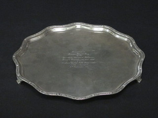 A shaped silver salver with bracketed border, raised on 3 scrolled supports, Sheffield 1957, inscribed, 27 ozs   ILLUSTRATED