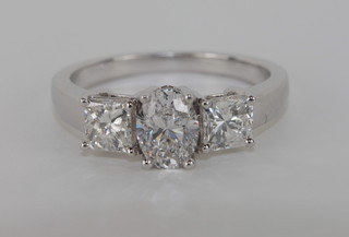 An 18ct white gold dress ring set an oval cut diamond and with 2 Princess cut diamonds to the shoulders, approx 1.78ct