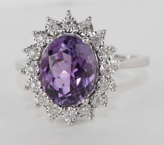 An 18ct white gold dress ring set an oval cut amethyst  surrounded by diamonds