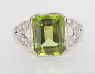 An 18ct yellow gold dress ring set a peridot supported by  diamonds
