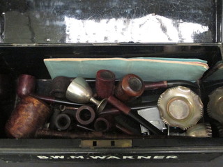 A rectangular metal deed box containing a collection of pipes