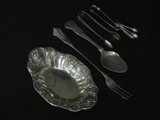 An oval Continental silver dish, a pair of silver plated sugar tongs, a miniature "silver" knife, fork and spoon, a pickle fork  and a butter scoop