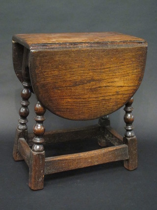 An oak drop flap occasional table raised on turned and block supports