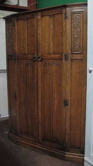 A carved oak wardrobe enclosed by panelled doors with linenfold decoration 50"