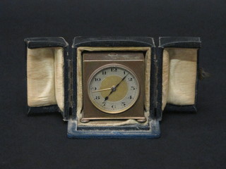 A 1930's alarm clock with silvered chapter ring and Roman  numerals contained in a gilt metal case 2"